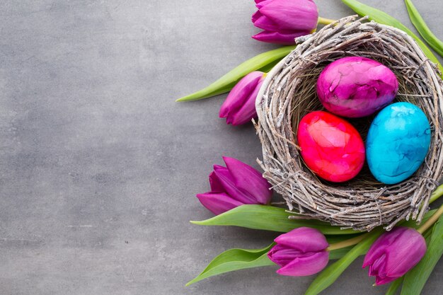 Huevos de Pascua en el nido con tulipanes alrededor.