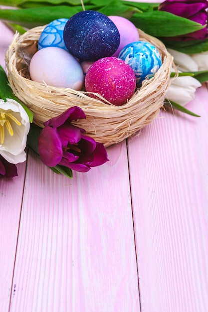Huevos de Pascua en un nido y tulipanes en tablones de madera