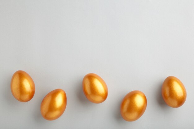 Huevos de Pascua de oro sobre pared gris. Concepto de primavera.