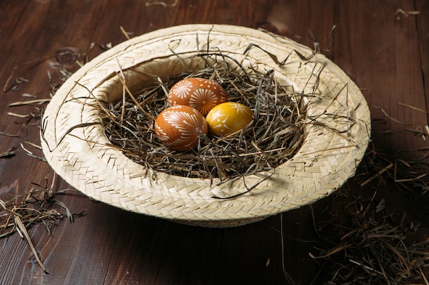 Huevos de Pascua en paja sobre fondo de madera oscuro