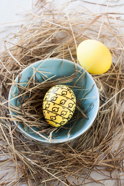 Huevos de Pascua con paja y un tazón