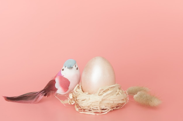 Huevos de Pascua y un pájaro sobre un fondo rosa claro.