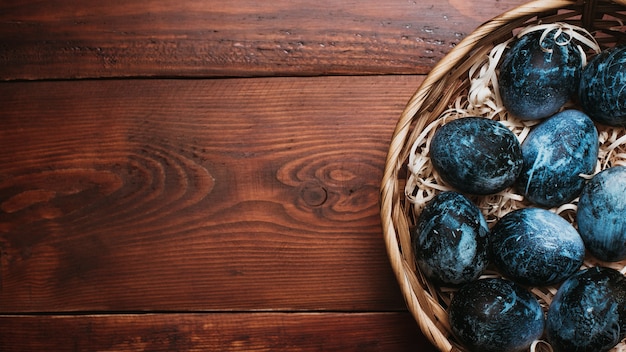 Huevos de Pascua pintados de azul en una canasta sobre un fondo de madera