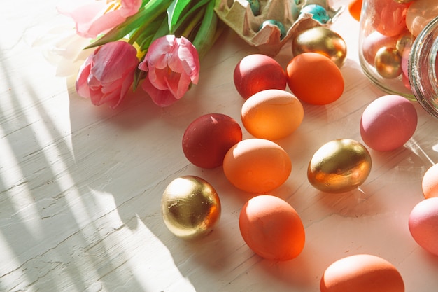 Huevos de Pascua pintados en una caja de huevos con tulipanes frescos de cerca