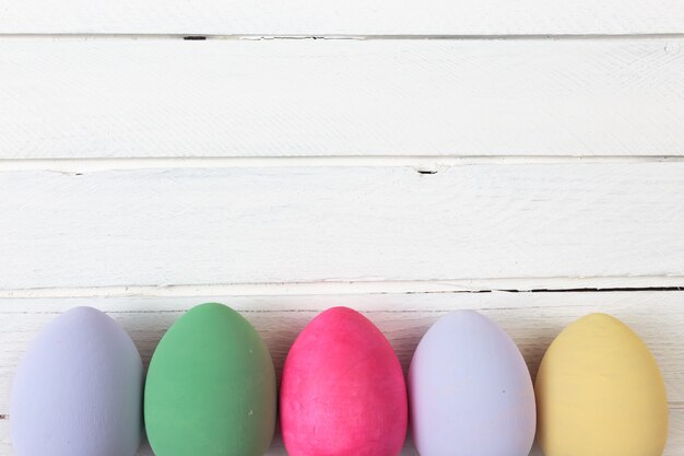 Huevos de Pascua pintados en colores pastel sobre un fondo de madera blanca