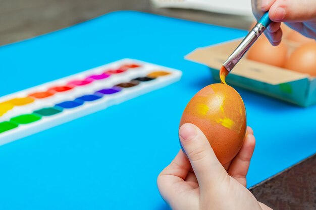 Huevos de Pascua pintados a mano antes de Pascua. Preparándose para la Pascua, sobre un fondo azul. Pintura multicolor, copie el espacio.