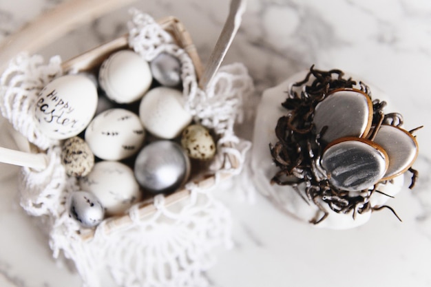 Huevos de Pascua pintados de plata y blancos sobre un fondo claro y espacio libre de postal de pastel para enfoque selectivo de texto