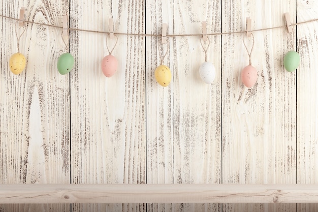 Huevos de Pascua en pinzas para la ropa sobre fondo de madera