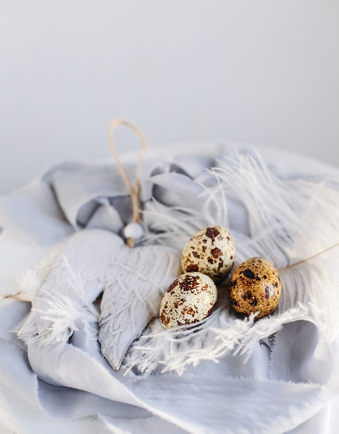 Huevos de Pascua con pluma blanca sobre fondo blanco y gris. Felices vacaciones de Pascua, vista frontal y superior.