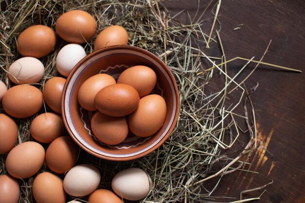 Los huevos de Pascua de pollo caseros se encuentran en el heno y en un tazón