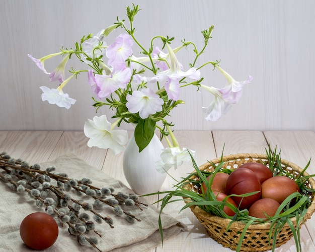 Huevos de Pascua y ramo de petunias sobre una mesa blanca.