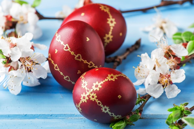 Huevos de Pascua rojos flores blancas y ramas de sauce sobre un suave fondo de madera azul de Pascua