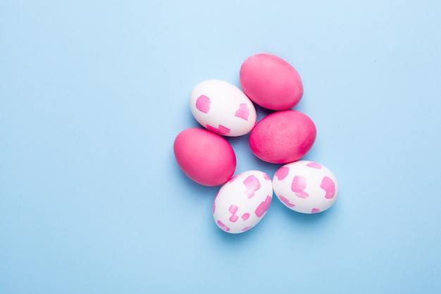 Huevos de Pascua rosa con pinceladas de acuarela sobre una superficie azul