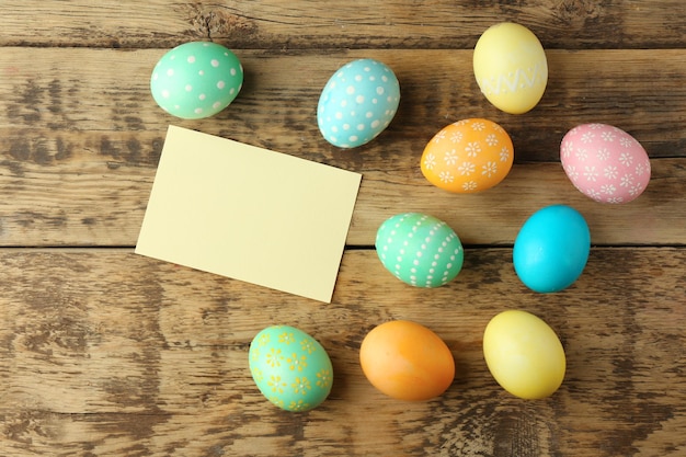 Huevos de Pascua sobre fondo de madera con tarjeta en blanco