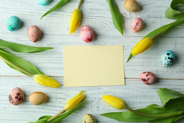 Huevos de Pascua sobre fondo de madera con tarjeta en blanco