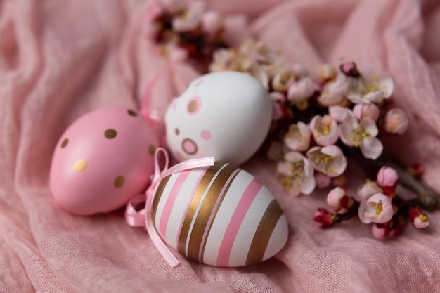 Huevos de Pascua sobre un fondo rosa con un ramo de flores.