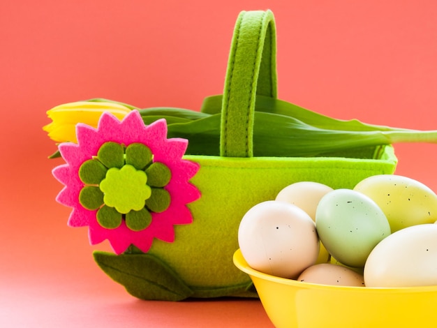 Huevos de Pascua en tazón de fuente amarillo y canasta decorativa.