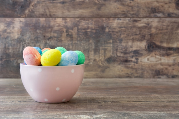 Huevos de Pascua en un tazón vintage en mesa de madera