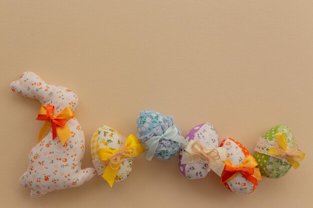 Huevos de Pascua de tela decorados con arcos de colores y conejito de Pascua de tela sobre un fondo claro