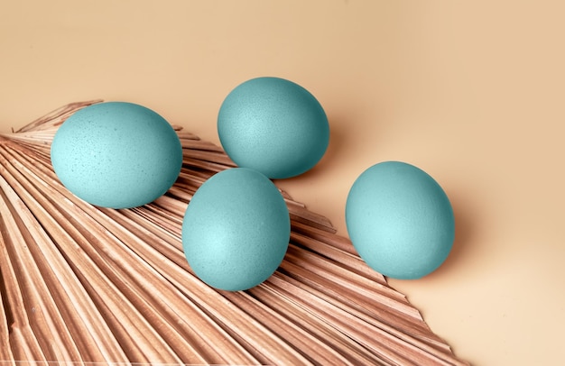 Huevos de Pascua teñidos de color azul pálido pastel y composición mínima de hojas secas para las fiestas religiosas de primavera