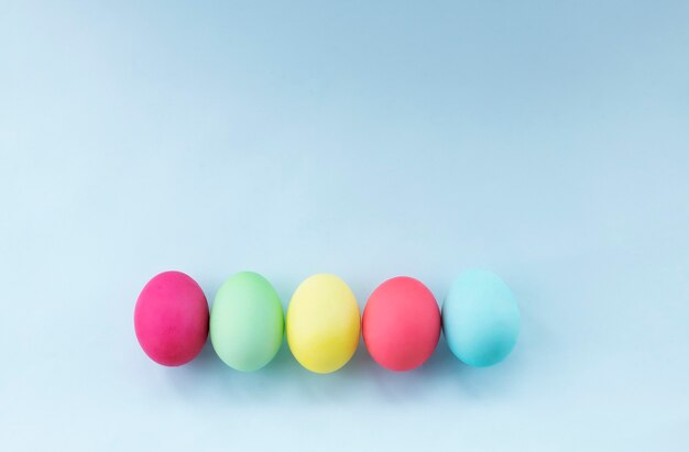 Huevos de Pascua teñidos en colores pastel contra la imagen de fondo azul claro con espacio de copia