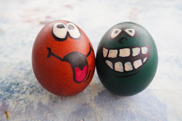 Huevos de Pascua teñidos de verde y marrón con caras de risa pintadas Muecas divertidas con ojos lengua y grandes dientes blancos Cara aterradora para Halloween Emoticon para Pascua Fondo abstracto claro