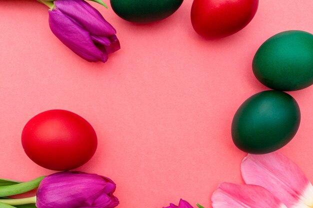 Huevos de Pascua con tulipanes de colores sobre un fondo rosa primavera.