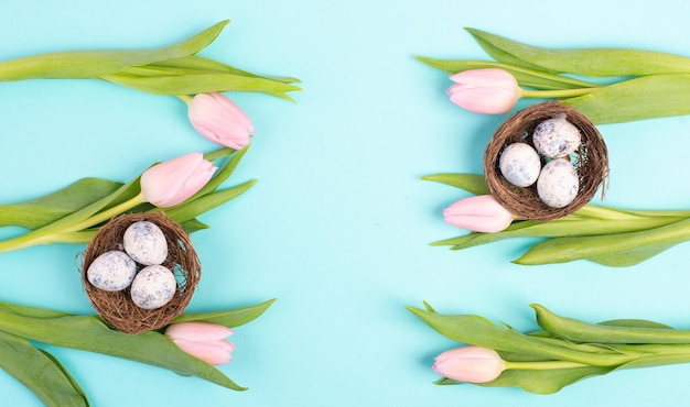 Huevos de Pascua y tulipanes rosas sobre un fondo de color azul, tarjeta de felicitación navideña, temporada de primavera