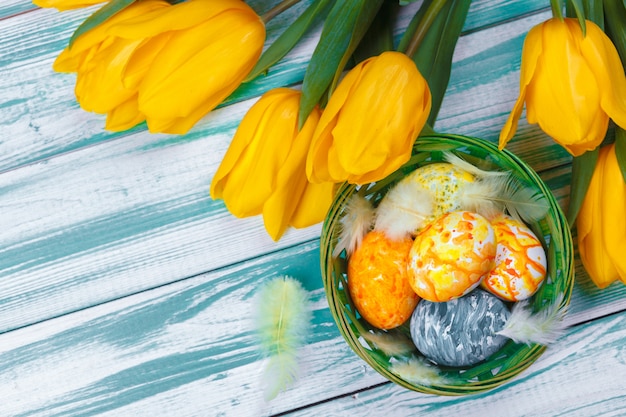 Huevos de Pascua con tulipanes sobre fondo de madera azul