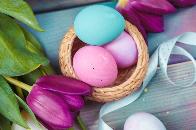 Huevos de Pascua con tulipanes sobre fondo de madera azul