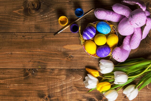 Huevos de Pascua y tulipanes en tablones de madera, conejito