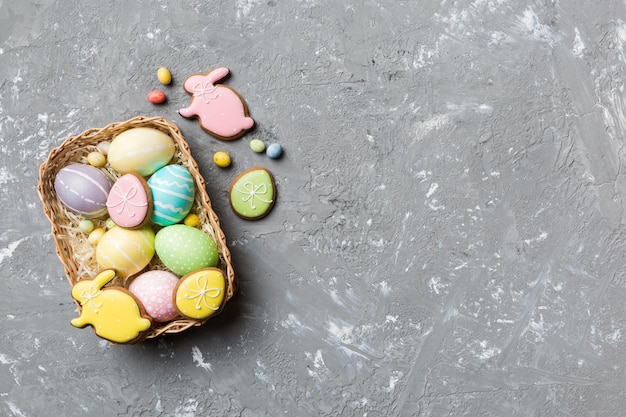 Huevos de Pascua de varios colores en la canasta tejida sobre fondo de color Concepto de vacaciones de huevos de Pascua de color pastel con espacio de copia