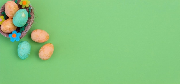 Huevos de Pascua verdes y naranjas en un nido sobre un fondo verde Espacio de copia plana Banner