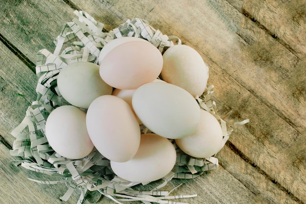 Huevos de pato frescos decorados en nidos de papel, frustrados en suelos de madera.