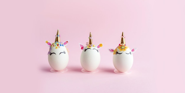 Huevos pintados con tema de unicornio sobre superficie rosa. Concepto de pascua