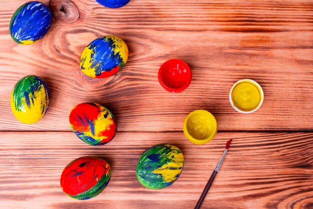 Huevos, pinturas y cepillo multicolores de Pascua en una tabla. Preparación para unas vacaciones.