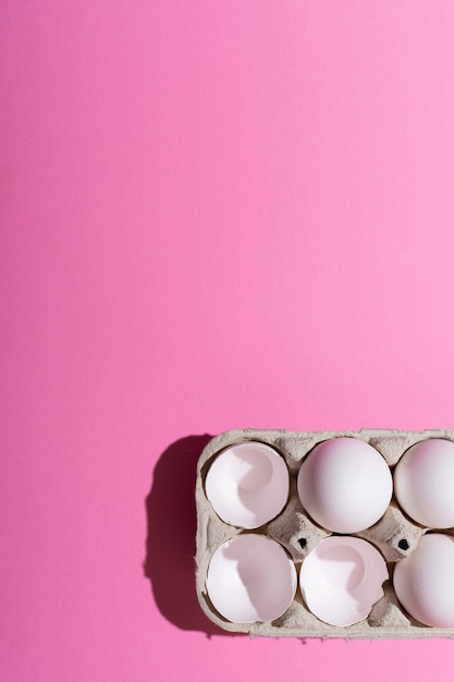 Huevos de pollo en una caja de cartón sobre un fondo rosa Cáscara de huevos vacíos batidos Resalte el concepto de la multitud