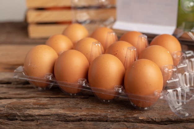 Huevos de pollo en una caja de plástico colocada sobre una mesa de madera.