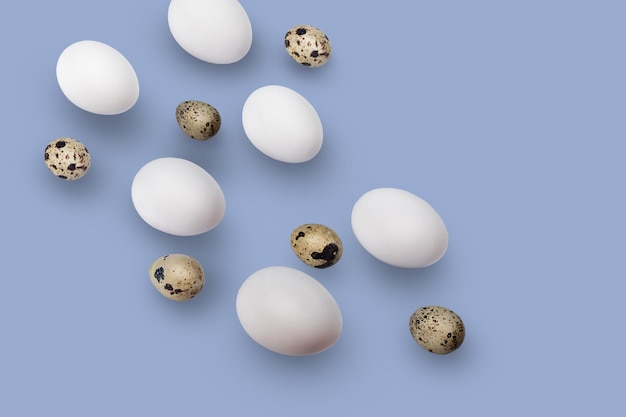 Huevos de pollo y codorniz aislado sobre un fondo azul.