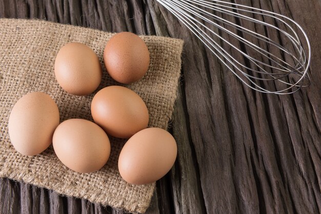 Huevos de pollo crudos en tela de tela de saco en madera marrón vieja