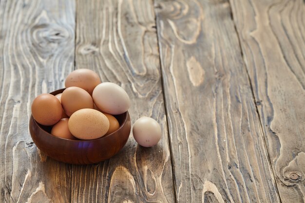 Huevos de pollo fresco pueblo sobre fondo de madera oscura. Comitiva de Pascua. Cesta o zócalo. texto libre, copia espacio.