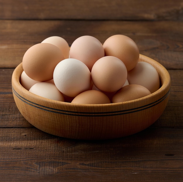 Huevos de pollo marrones frescos en un plato redondo de madera sobre la mesa