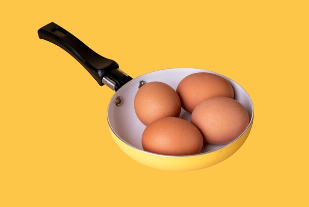 Huevos de pollo saludables naturales en cáscara beige en sartén sobre fondo amarillo