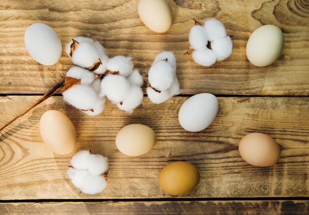 Huevos y una rama con flores de algodón blanco con sombras soleadas sobre un fondo de madera. Una tarjeta de vacaciones. El concepto de la fiesta de Pascua. decoraciones de Pascua.