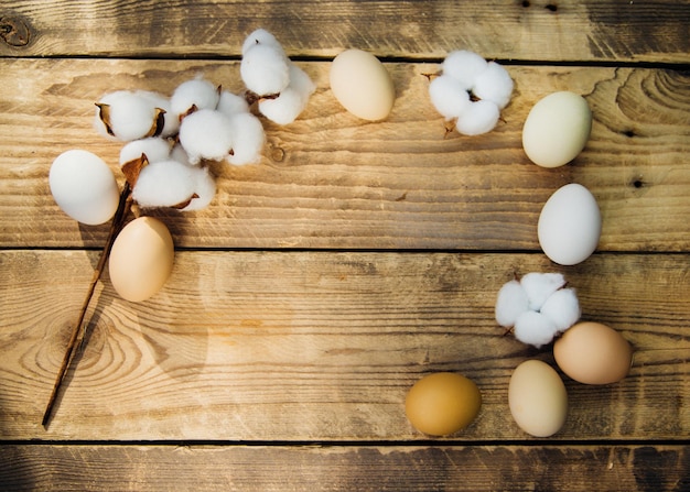 Huevos y una rama con flores de algodón blanco con sombras soleadas sobre un fondo de madera. Una tarjeta de vacaciones. El concepto de la fiesta de Pascua. decoraciones de Pascua.