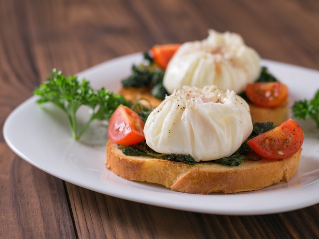 Huevos recién escalfados en rebanadas de pan en un plato blanco. Merienda vegetariana con huevos escalfados.