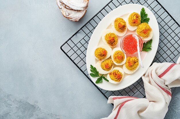 Huevos rellenos con caviar rojo y pimentón en placa para aperitivo mesa de pascua