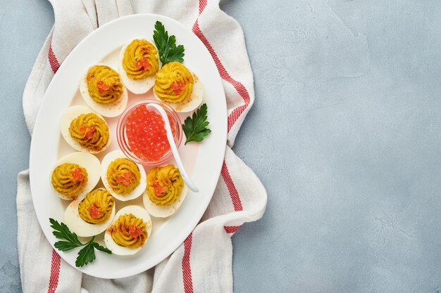 Huevos rellenos con caviar rojo y pimentón en placa para aperitivo mesa de pascua