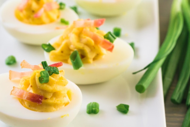 Huevos rellenos con guarnición de cebollas verdes y tocino.