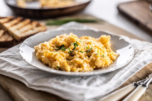 Foto los huevos revueltos frescos y calientes de aspecto sabroso se sirven en un plato con una salpicadura de cebolla fresca en la parte superior